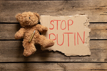 Teddy bear and bullet next to sign and text stop Putin on wooden table ,War in Ukraine with Russia