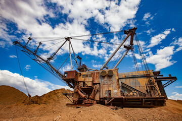 Aluminium ore mining and transporting. Bauxite clay mine. Soviet old rusted walking dragline excavator in quarry. On blue sky with clouds. Arkalyk, Kostanay province, Kazakhstan.