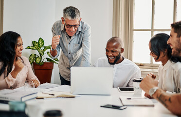 When you finally see your designs online. Shot of a group of businesspeople cheering while using a laptop during a meeting in a modern office.
