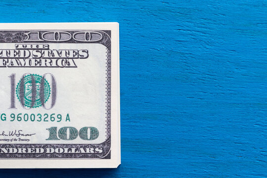 A wad of USA dollars on a blue wooden background and a copy space.