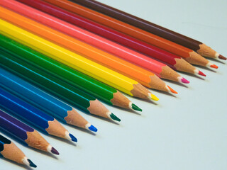 Diagonal view of a row of colored pencils over a blue background. Colour crayons.