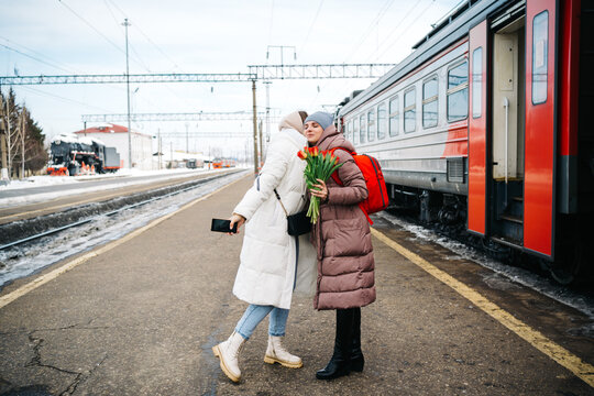 girls say goodbye hugging on the station platform