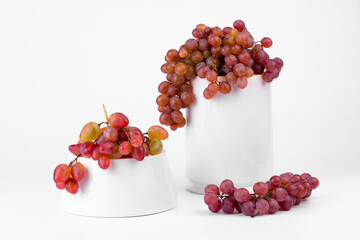 Grapes bunch. Grapes on light background and white ceramic platform (podium) with grapes bunch. Creative autumn background.