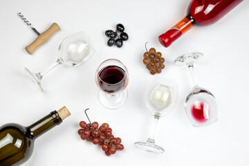 Wine bottles and glasses with different wine, corkscrews and grape bunches on grey background. Top...