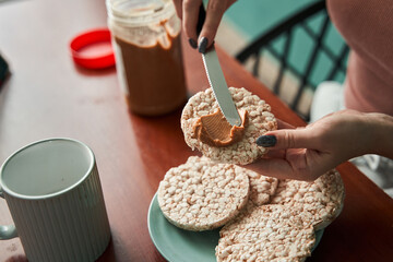 Woman making toasts from the loaves and putting peanut butter on it while preparing her breakfast - Powered by Adobe