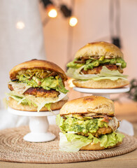 Close-up of tasty, home-made vegan hamburger on rustic table with fresh vegetables around.