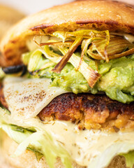Close-up of tasty, home-made vegan hamburger on rustic table with fresh vegetables around.