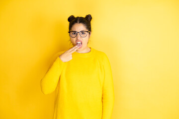 Young beautiful woman wearing casual sweater over isolated yellow background disgusted with her...