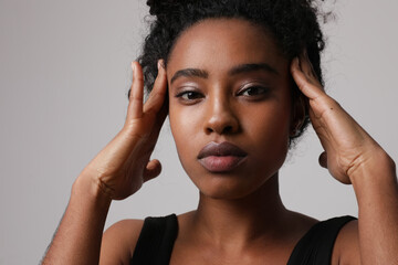 Obraz premium Headshot of African American woman touches her head and looking at the camera.