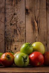 unripe tomatoes on brown wooden kitchen rustic background. Farmer fresh organic product. Vegan eco-friendly no animal food, copy space, vertical shot