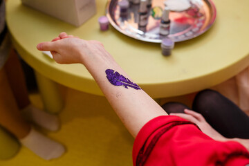 Izmail, Ukraine. January 2021. Close up of kids doing glitter flash tattooes on birthday party.