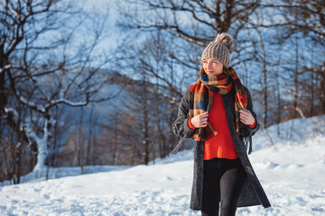 Fototapeta na wymiar Young woman in the winter time walks among snow