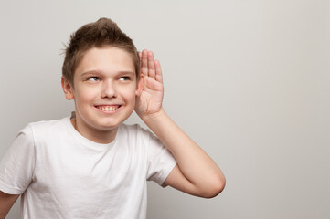 caucasian young boy dressed in the white t-shirt listening through the silence
