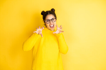 Young beautiful woman wearing casual sweater over isolated yellow background smiling funny doing...