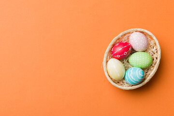 Multi colors Easter eggs in the woven basket on colored background . Pastel color Easter eggs. holiday concept with copy space