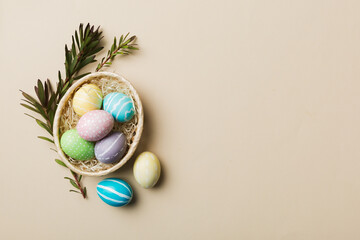 Multi colors Easter eggs in the woven basket on colored background . Pastel color Easter eggs....