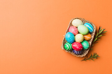 Multi colors Easter eggs in the woven basket on colored background . Pastel color Easter eggs. holiday concept with copy space