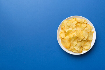 Potato chips on bowl isolated on colored background. Delicious crispy potato chips in bowl. Space for text. Top view