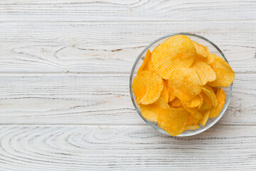 Potato chips on bowl isolated on colored background. Delicious crispy potato chips in bowl. Space...