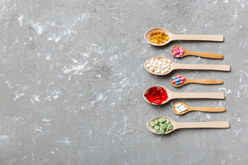Top view Variety of vitamin and mineral pills in wooden spoon on Colored background. Top view of assorted pharmaceutical medicine pills. Dietary supplement healthcare product