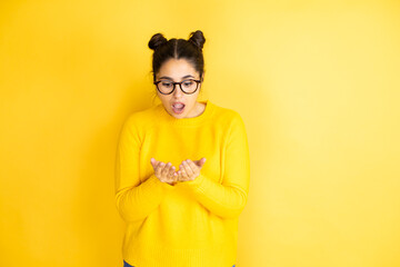 Young beautiful woman wearing casual sweater over isolated yellow background Smiling with hands palms together receiving or giving gesture. Hold and protection