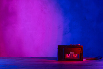 Vintage cassette tape player in neon light. 80s - 90s advertisement style. Disco party nostalgy...