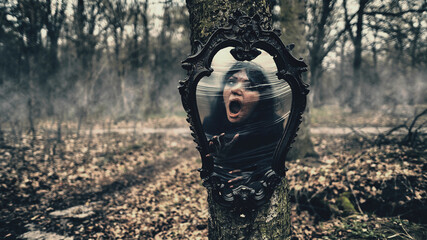 emotional witch in the mirror on a background of scary forest