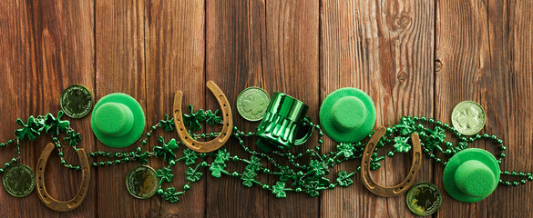 St Patricks Day border of shamrocks beads and coins over a rustic wood background
