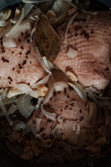 Pieces of sliced fresh chicken with skin stacked in a saucepan.