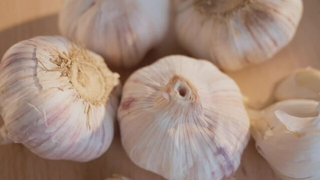 Macro shot from above of garlic bulbs and cloves, spinning on a wooden surface.