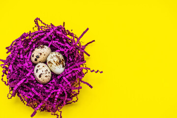 Obraz premium Happy Easter card. Easter eggs on the background of a purple nest, top view on a yellow background, image with selective focus. Copy space for text.