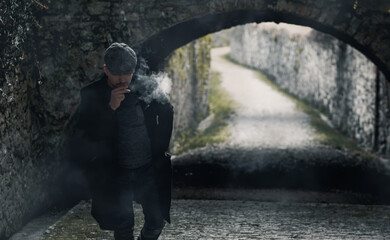 Man in vintage clothing smokes cigarette.