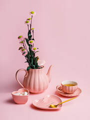 Pink cup of coffee, kettle and plate with bouquet of fresh flowers on pastel pink background....