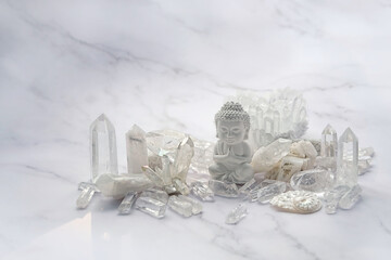 Clear quartz minerals and Buddha statue on light marble background. gemstones crystals for healing...