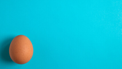 Chicken egg on a blue background. Copy space. Minimal concept.