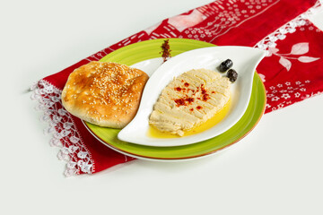 Houmus with pita bread in a dish isolated on colorful table cloth top view on grey background