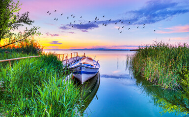 paisaje de colores de un lago al amanecer con una barca en el viejo embarcadero de madera