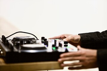 A view of a dj mixer and decks with headphones. Close-up of arms of Dj playing and mixing a track on dj controllers. Disc jockey playing music at the party. Professional DJ works on the equipment.