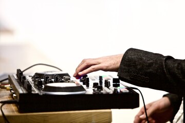 A view of a dj mixer and decks with headphones. Close-up of arms of Dj playing and mixing a track...