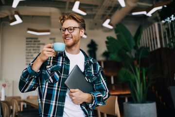 Young guy drinking tea or coffee in office space - Powered by Adobe