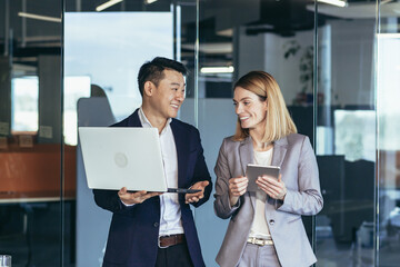 A group of business people stand in the hallway and discuss about problems in the company. Person...