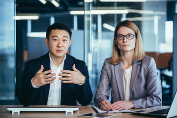 a team of business employees at an online meeting look at camera and communicate. Webcam view. conference remote interview. Two office workers talking Video call conversation. Asian male and female