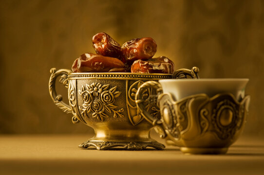 Arabian finest date fruits in an ornamental bowl. Classic Arabic teacups and a bowl of dates.