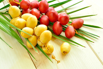 A bunch of raw yellow and red color dates with palm leaf. Product of Middle eastern date farming. 