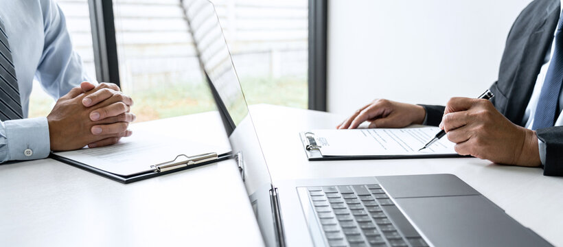 Senior committee manager reading a resume during a job interview, Employer interviewing to ask young male job seeker for recruitment talking in office