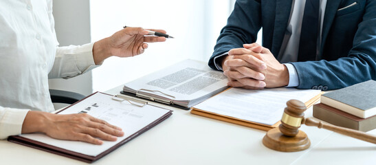 Male lawyer is pointing on legal document to explaining about consultation terms and condition to businesswoman before signing on contract at law firm - obrazy, fototapety, plakaty