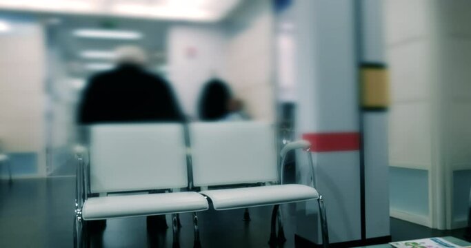 Rear view of unrecognizable persons sitting on the bench in doctors waiting room - clean blue color grading