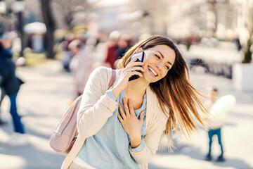 A laughing woman having phone conversation in a park.