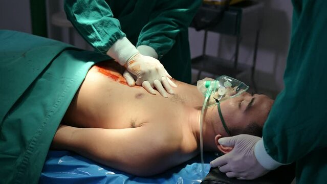 Team of doctor and assistant helping by CPR with accident injured patient unresponsive in operating room