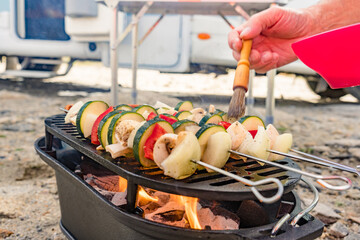 Grilled vegetables on barbecue grill. Rv in the distance